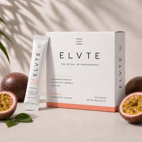 ELVTE Performance Hydration Energy+ passionfruit flavour sachet box and single stick pack, styled with fresh passionfruit halves and green leaves on a beige surface with leaf shadows.